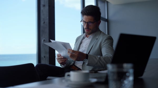 businessman-studying-documents-papers-near-laptop-in-office-pensive-manager-looking-co-SBI-351394449-1